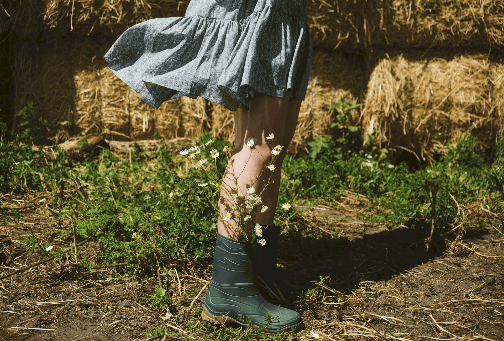 Girl with flowers sticking out of her raiboots.