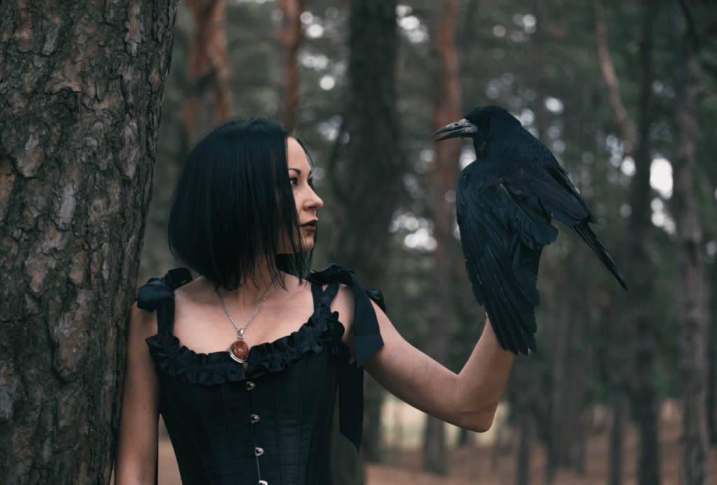 Woman with black clothes and a raven on her hand
