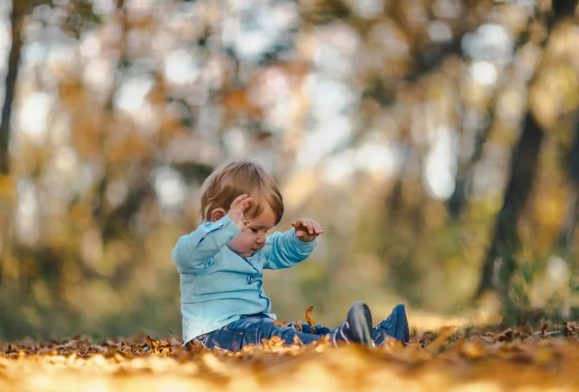 baby boy playing in leaf pile