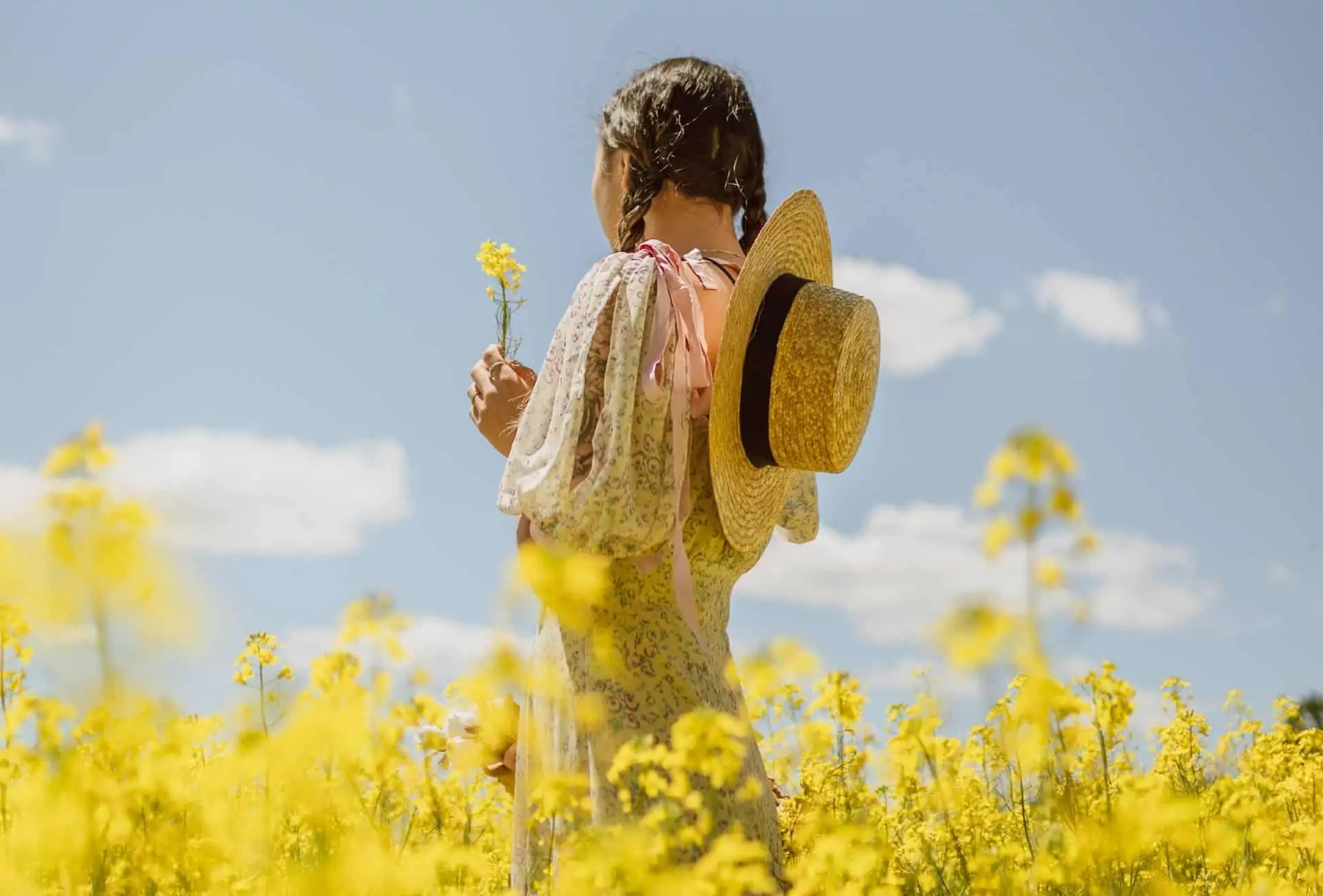 Woman wearing a cottagecore dress in yellow flower field.