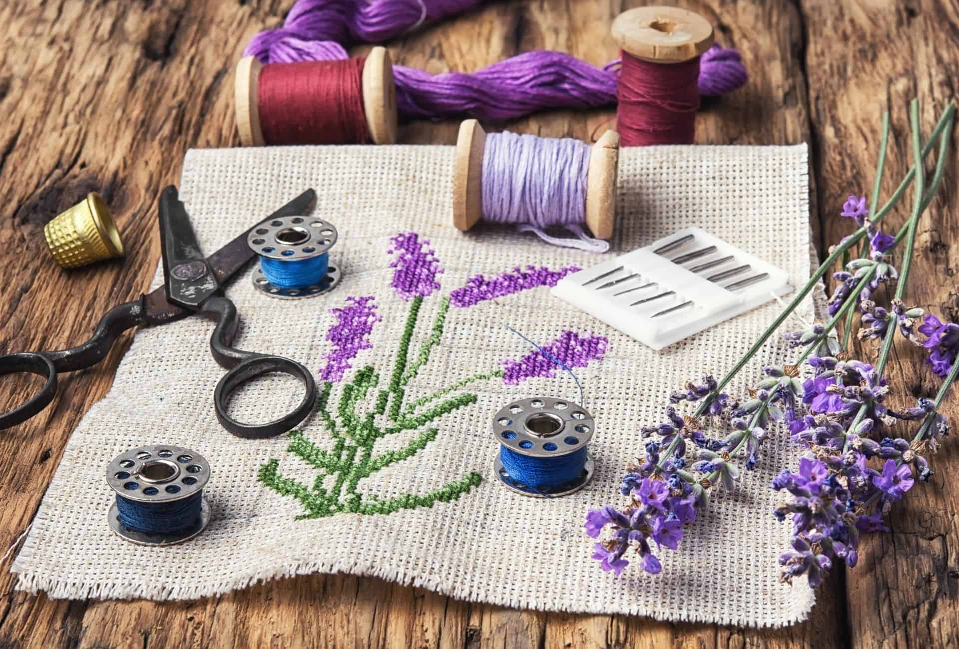 Lavender embroidery is arranged on the table with various tools.